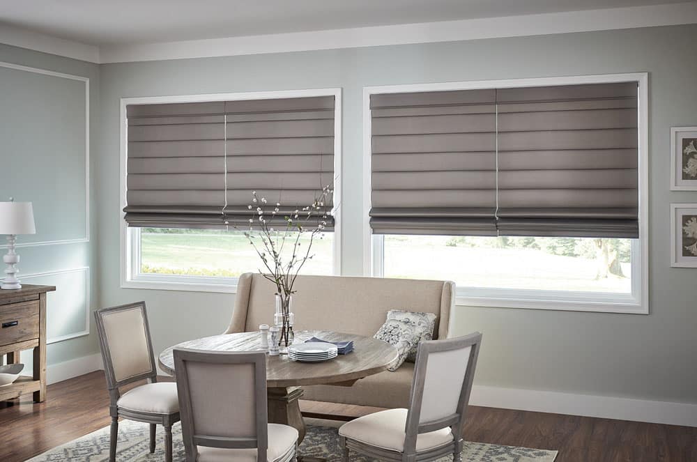Warm, naturally colored Graber Roman Shades pulled halfway up in a sitting room.